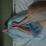 A cancer patient sitting on a hospital bed, viewed from above (Photo: Tima Miroshnichenko)